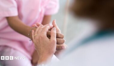 A stock image of a patient's hands holding a carer's hands. Just the hands are in shot.