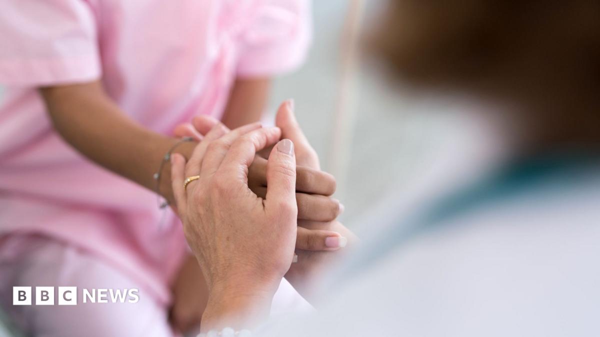 A stock image of a patient's hands holding a carer's hands. Just the hands are in shot.