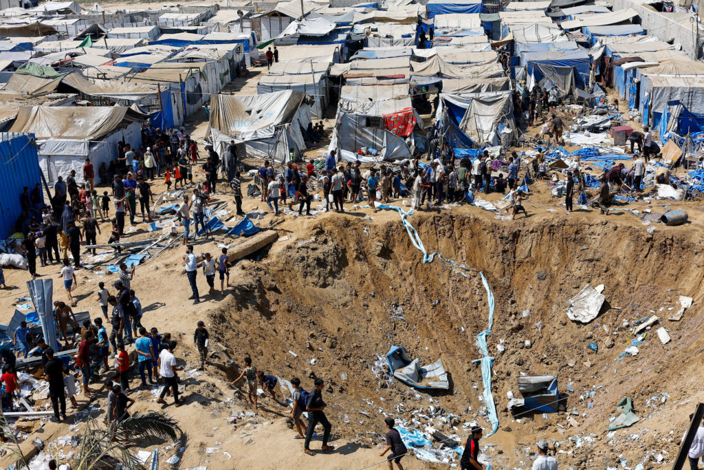 Palestinians inspect the site of an overnight Israeli strike on a medicine warehouse, in Deir al-Balah