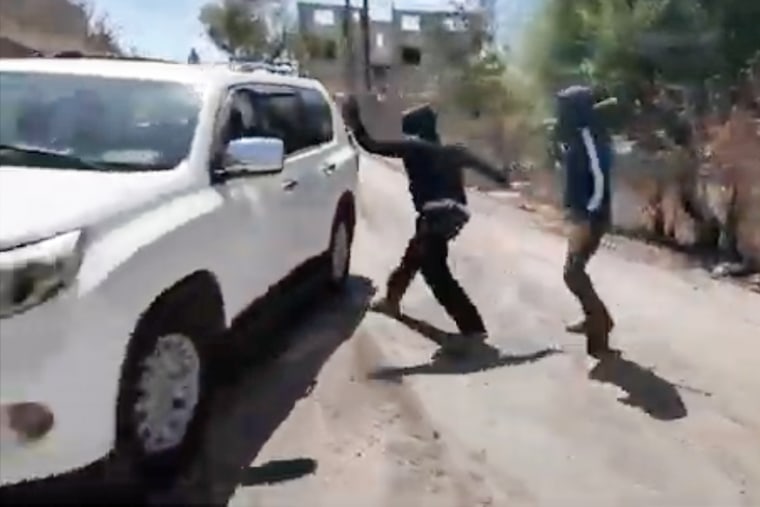 Masked attackers hit a car window as the car tries to escape