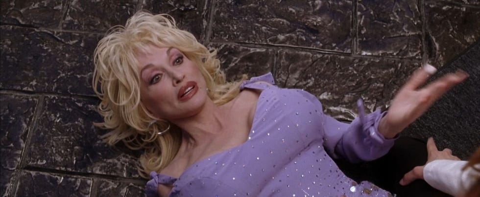 Dolly Parton in Miss Congeniality 2 dolly parton in miss congeniality 2 wearing a sparkly purple dress lying on a stone floor, with an exasperated expression