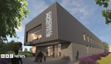 A computer-generated image of what the proposed GP surgery would look like. It is a double-storey building with a large window to its front and glass-panelled front. There are gardens around the building.
