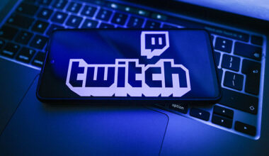 In this photo illustration, a Twitch logo is seen displayed on a smartphone on the top of a laptop.