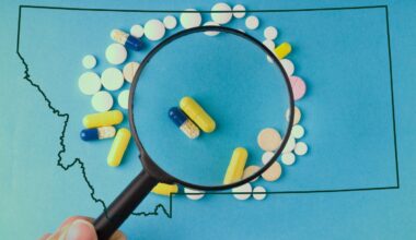 A photo illustration of a hand holding a magnifying glass over a scattering of prescription pills, outlined by the shape of Montana.
