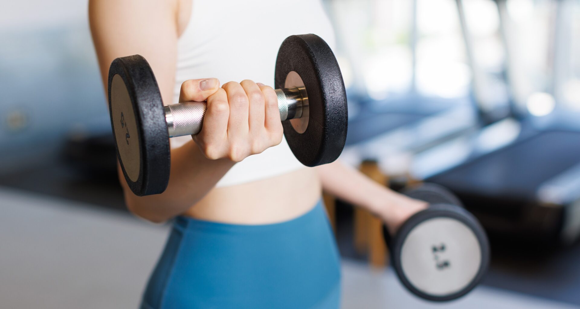 Woman training with dumbbells at a gym.