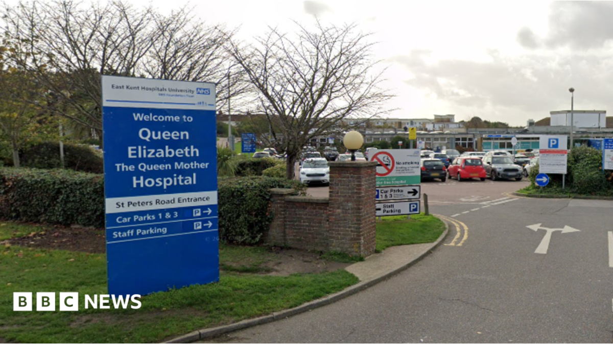 The main road entrance to the Queen Elizabeth the Queen Mother car park, with a blue sign to the left of the hospital's name