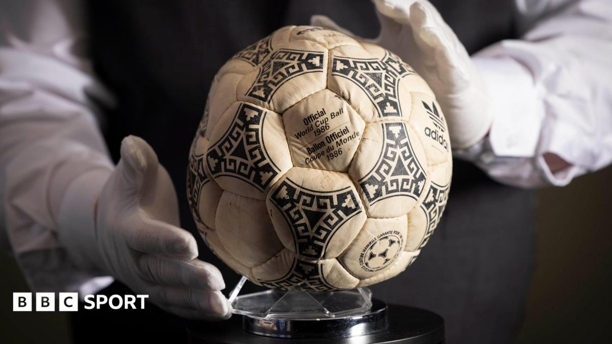 A person wearing white gloves places the football used in the 1986 World Cup quarter-final on a stand