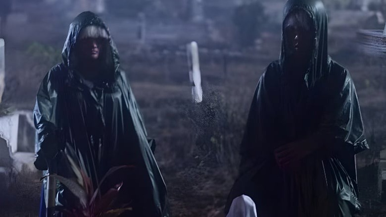 Two hooded figures standing next to each other on 