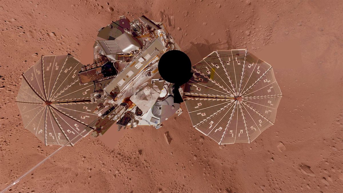 a planetary lander as seen from above showing its two circular solar arrays and main body atop a red surface