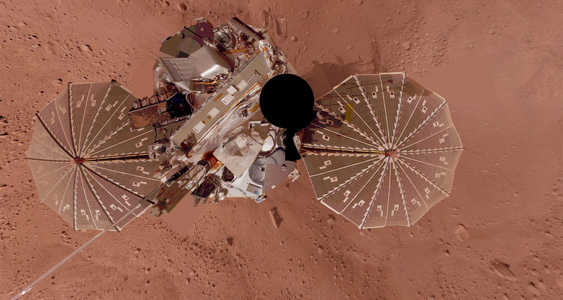a planetary lander as seen from above showing its two circular solar arrays and main body atop a red surface