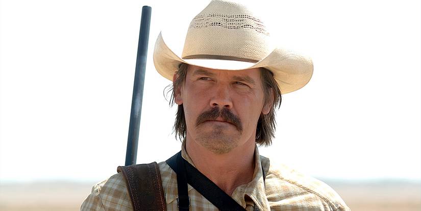 Josh Brolin as Llewelyn Moss with a gun on his back in the desert in No Country for Old Men.