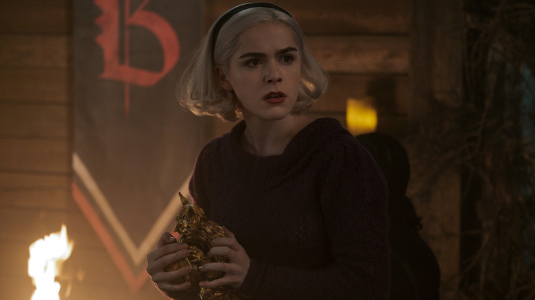 Sabrina (Kiernan Shipka) holding a gold statue on 