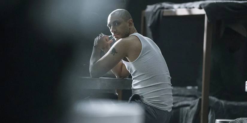 Riz Ahmed in a tank top and grey sweatpants, sitting in Rikers, in The Night Of