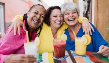 Three friends are having drinks and smiling.