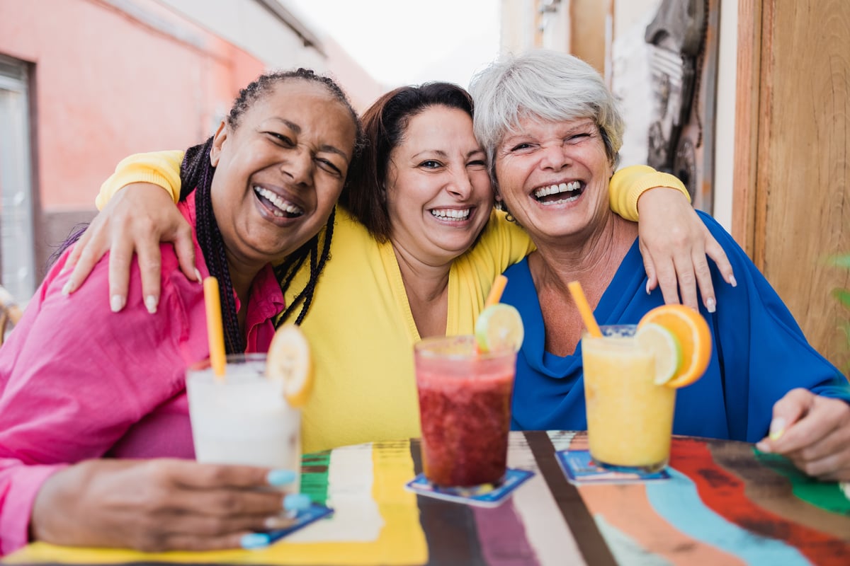 Three friends are having drinks and smiling.