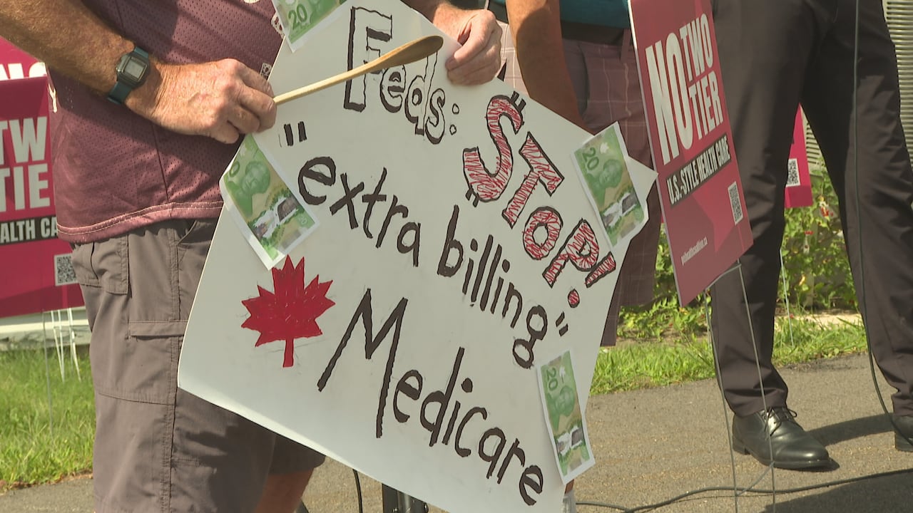 A person is seen holding a wooden spoon an white sign.