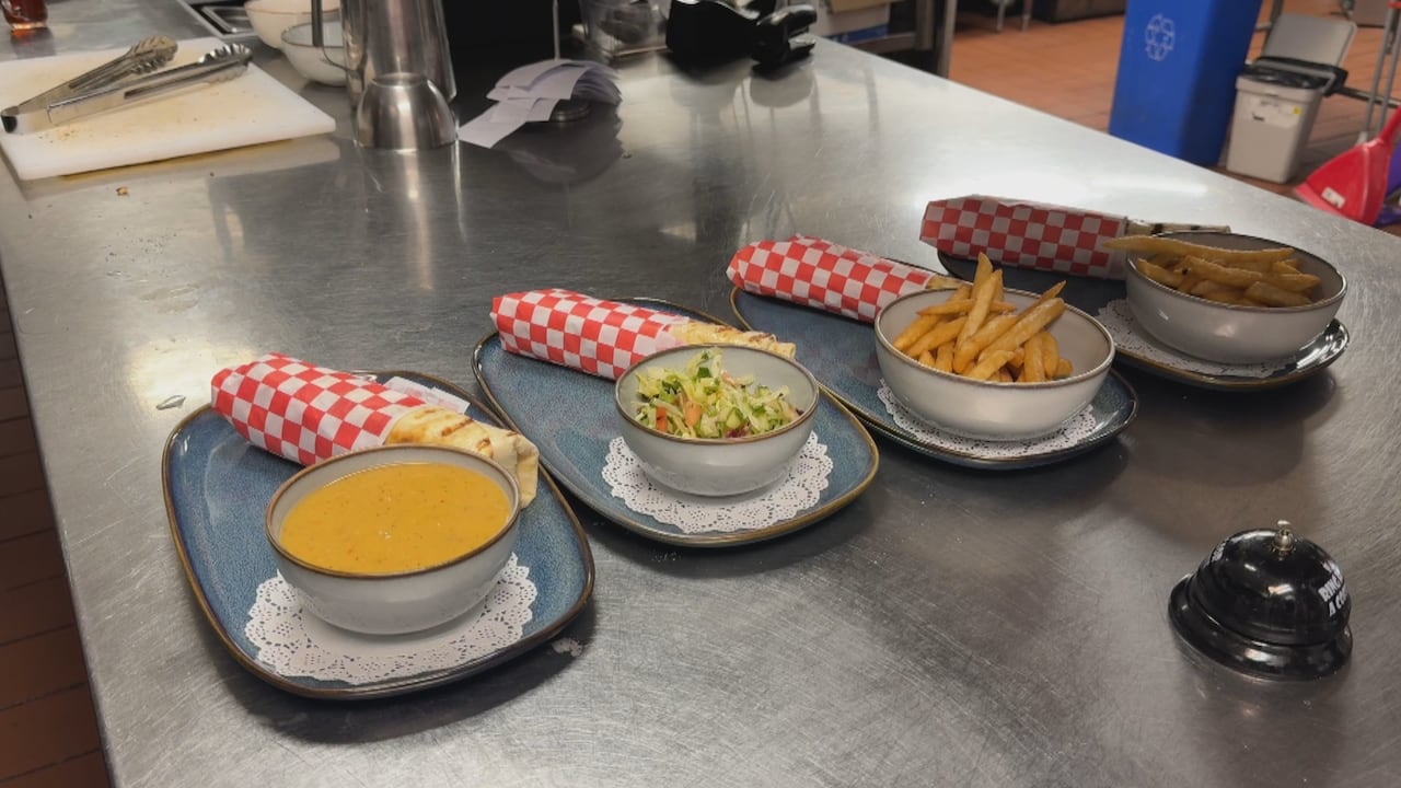 Four wraps on a table ready to be served, with sides including soup, salad and fries.