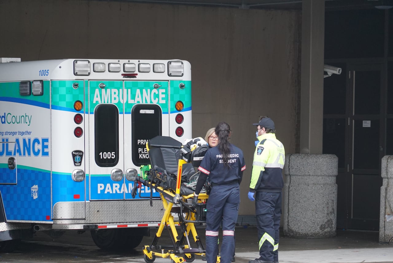 Ambulances and paramedics in the emergency bay at a hospital.