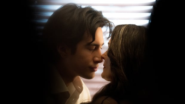 a film still of a young East Asian man embracing an older white woman.