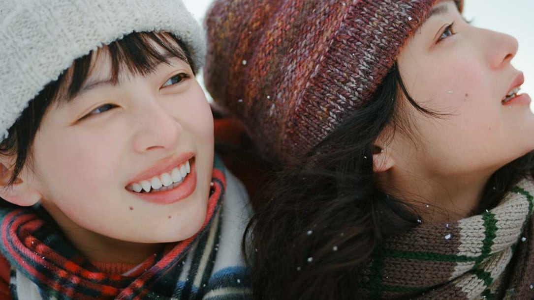 two young Japanese women smiling at snow.