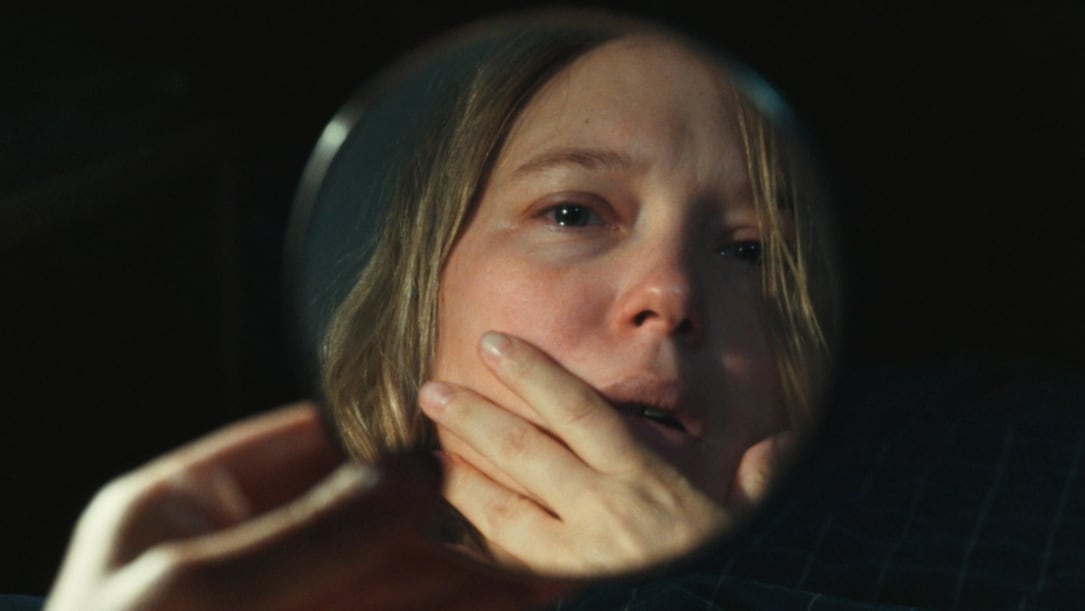 a white woman looks at herself in a mirror with horror.