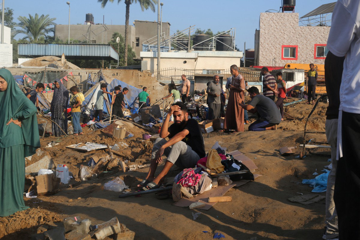 Displaced Palestinians salvage what remain of their belongings from destroyed tent-homes following an Israeli airstrike that targeted the nearby medical supplies and pharmaceuticals warehouse of Al-Aqsa Martyrs Hospital in Deir al-Balah, central Gaza Strip on August 1, 2026. (AFP)