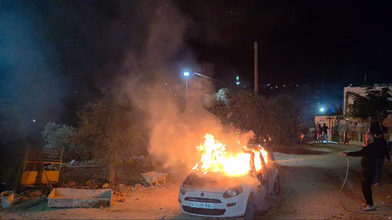 A car is seen on fire in the West Bank town of Kusra.