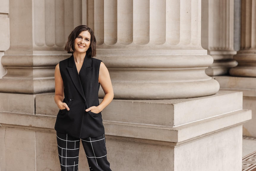 Financial planner Rebecca Pritchard smiles for a portrait. Her hands are in her pockets.