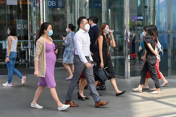Office workers walk out for a lunch break at Raffles Place financial business district in Singapore on May 10, 2022. Photo by AFP