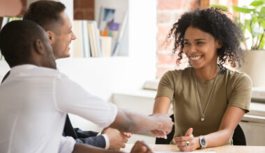 People shaking hands across a table.