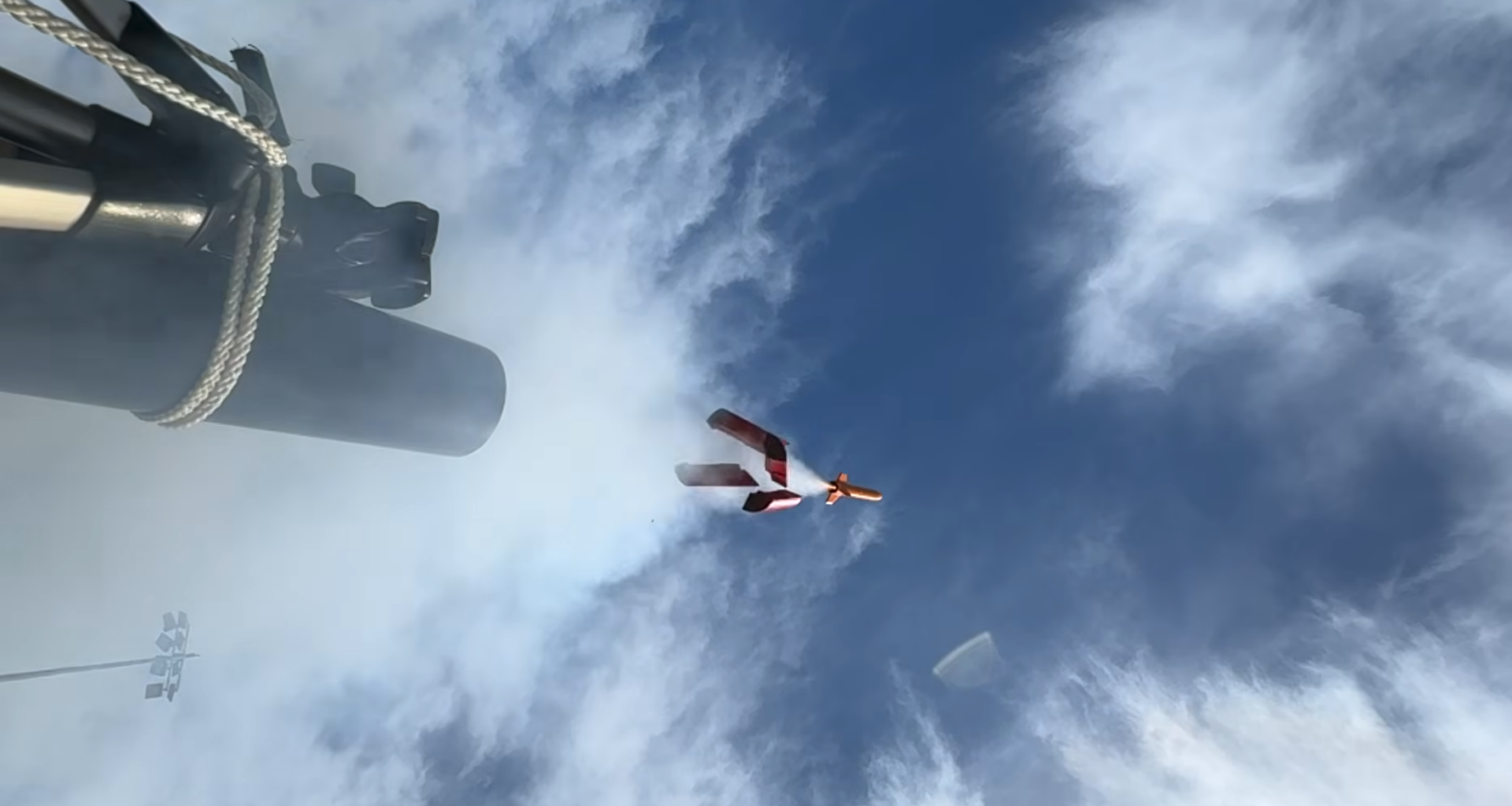 A small rocket is shown launching into the sky, with a trail of smoke leading into the mount of a black pipe. Four large plastic pieces are falling away from below the rocket.