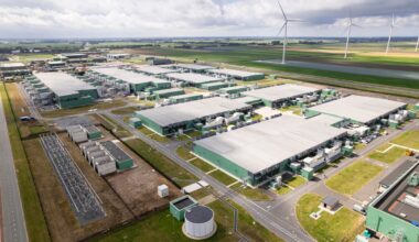 An expansive data center with wind turbines in the background.