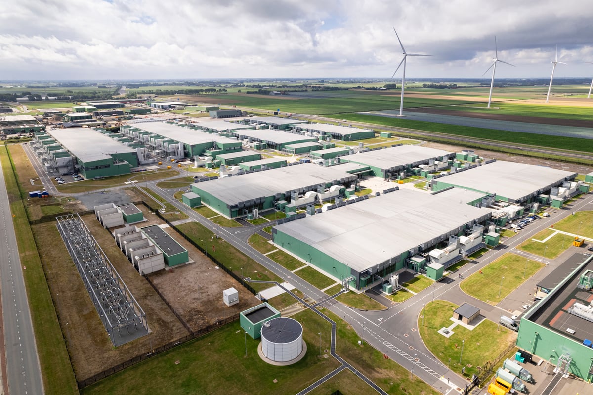 An expansive data center with wind turbines in the background.