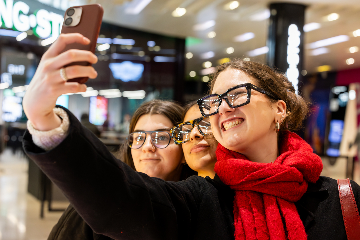 Three people wearing eyeglass frames smile for a selfie inside the store.