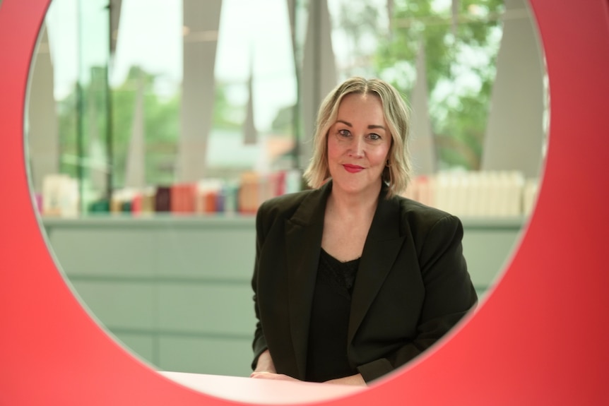 Woman smiles into a mirror wearing a black blazer
