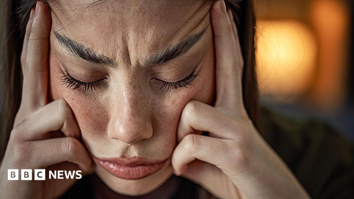 A woman looking stressed out wit her fingers pressed against her temples