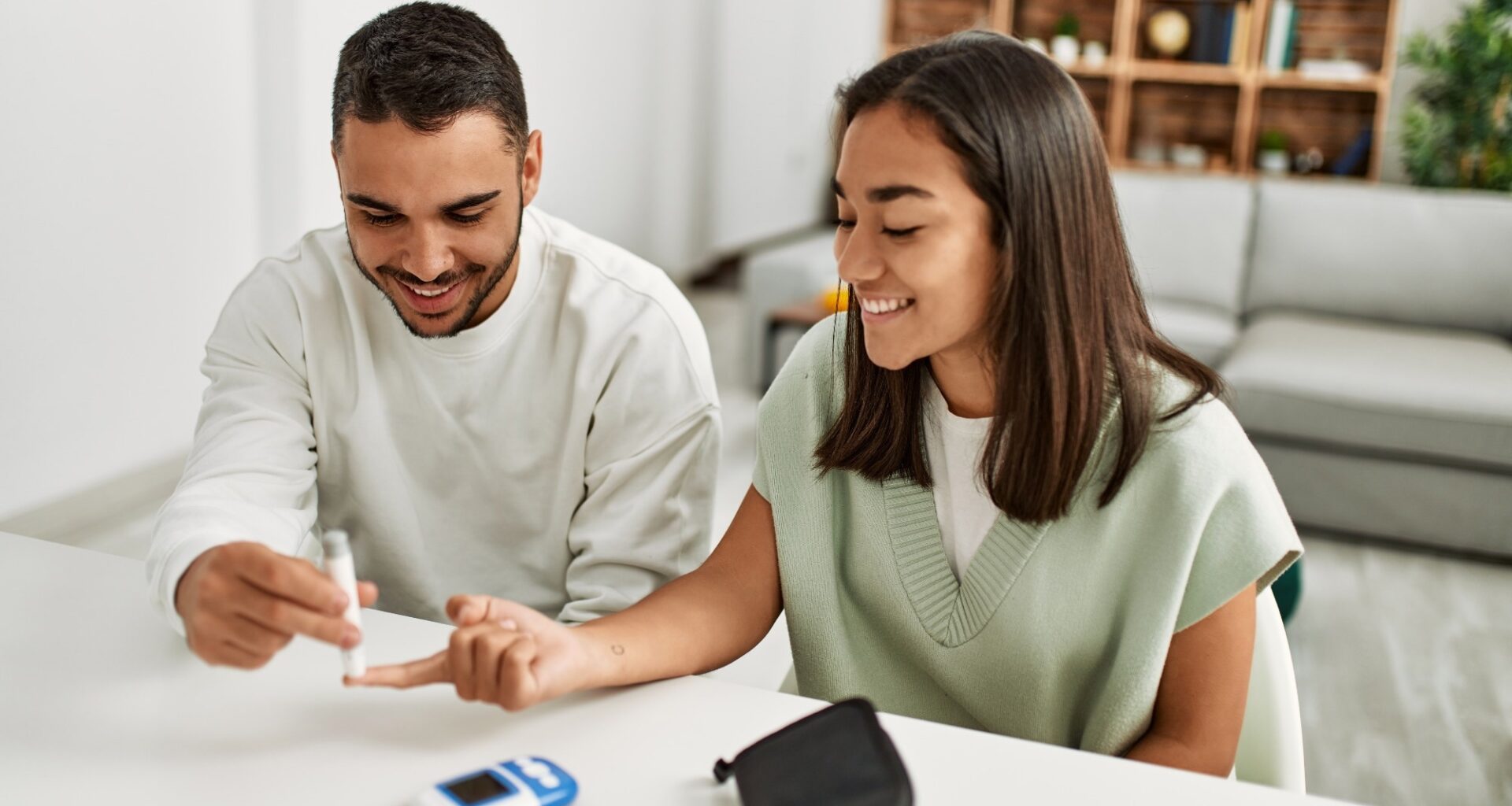 Young couple smiling happy measuring glucose at home.