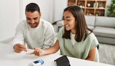 Young couple smiling happy measuring glucose at home.