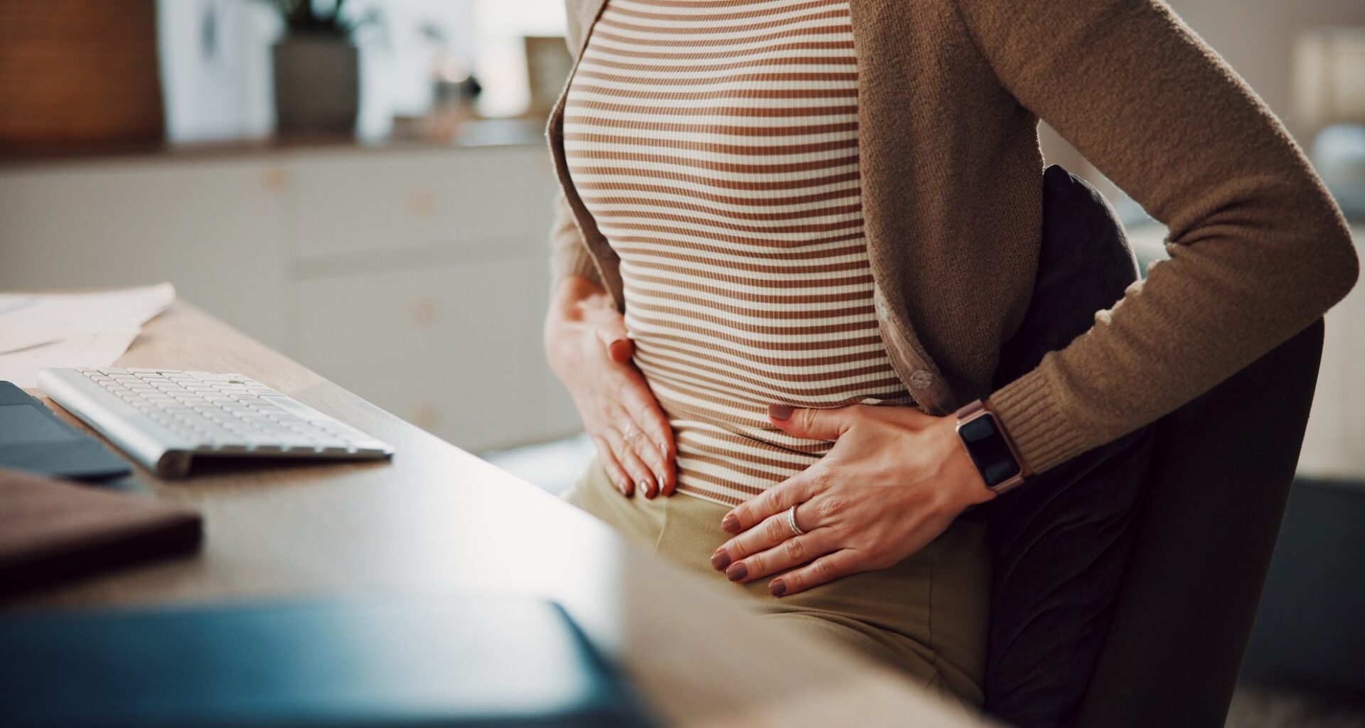 Hands, stomach ache or woman in home office with pain, menstrual cramps or gas with remote work.