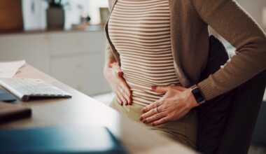 Hands, stomach ache or woman in home office with pain, menstrual cramps or gas with remote work.