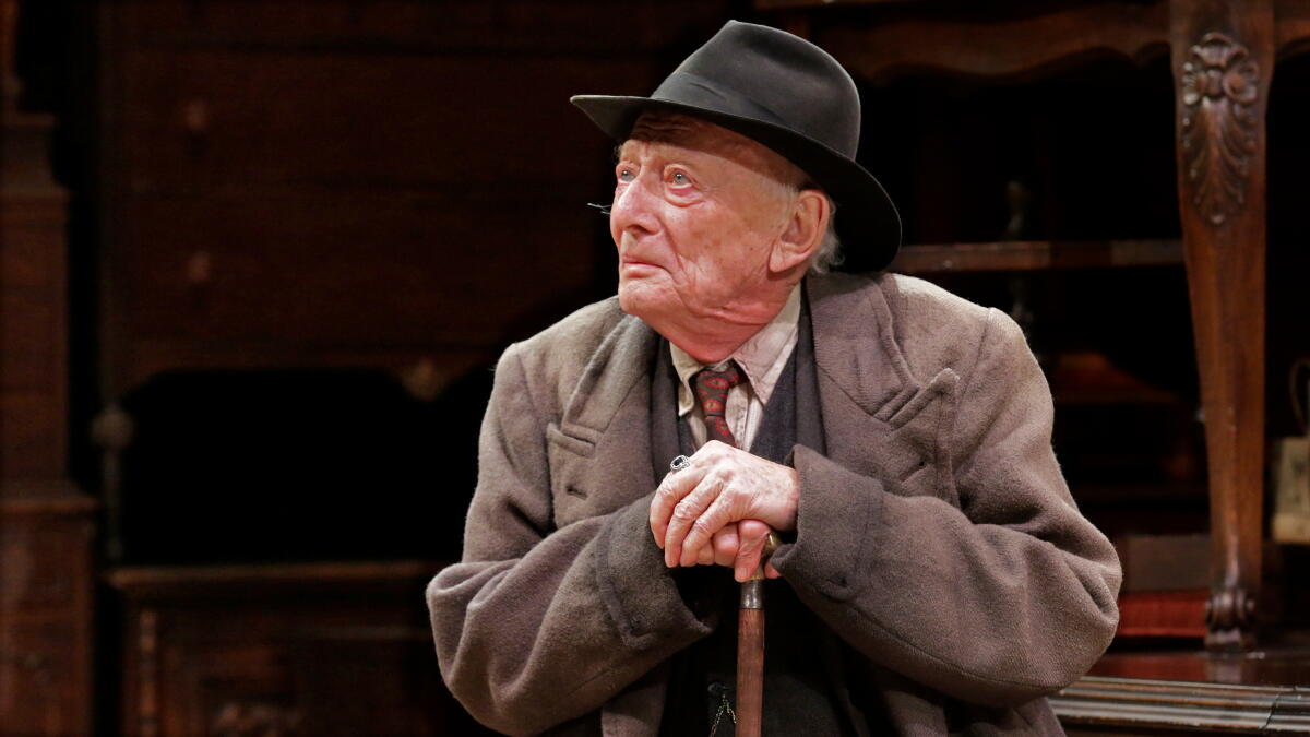 Alan Mandell as Gregory Solomon, wearing a coat and fedora, in Arthur Miller's "The Price." 