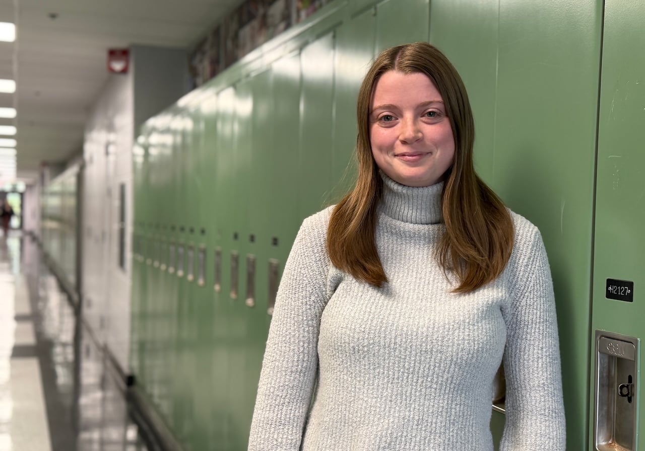 A student stands against a row of lockers