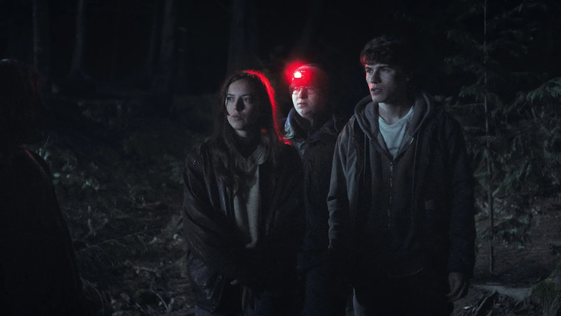 Sonny and his friends search a forest at night, one of them is wearing a bright red flashlight on their head