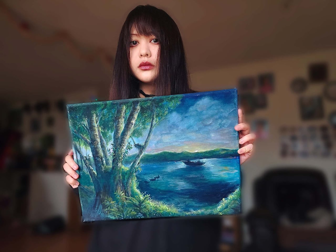 A female youth holding a canvas of a painting.