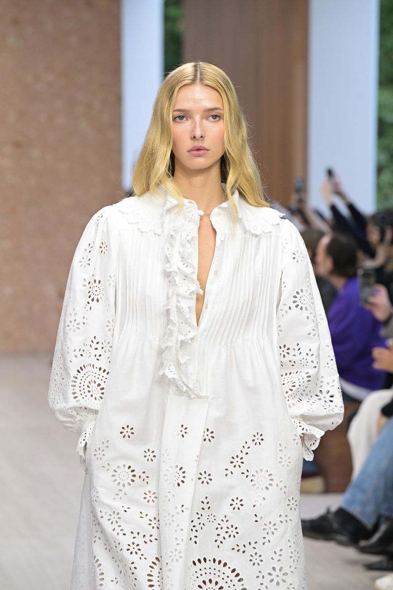 She walked in a billowing white dress featuring a plunging neckline, ruffled details, dramatic sleeves and intricate eyelet cutouts.