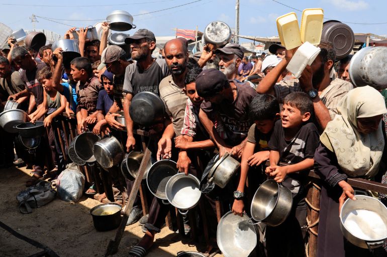 Palestinians hold pots and containers while waiting to receive food from a charity kitchen in Khan Younis, southern Gaza Strip, August 21, 2025. [Hatem Khaled/Reuters]