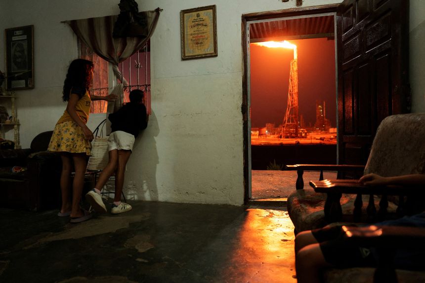 Children look out of a window as a gas flare burns at the Cardon refinery in Punta Cardon, Venezuela, May 6.