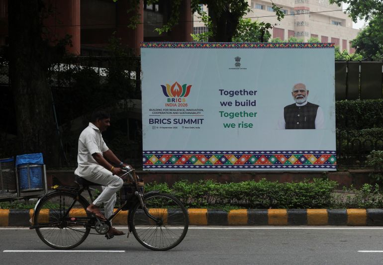 A man cycles past a hoarding featuring Indian Prime Minister Narendra Modi before the BRICS summit in New Delhi, India, on September 11, 2026