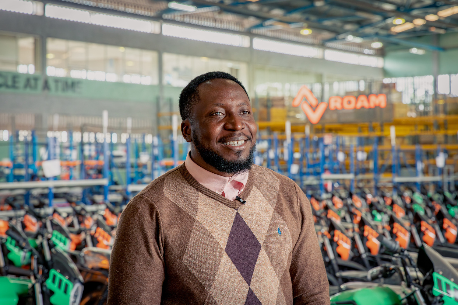 A man stands in front of a sign that reads Roam