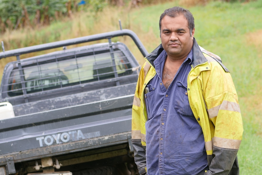 A man in high vis stands in front of a ute.